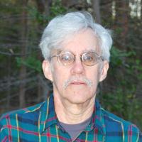 Person with short hair, glasses, and a blue plaid shirt