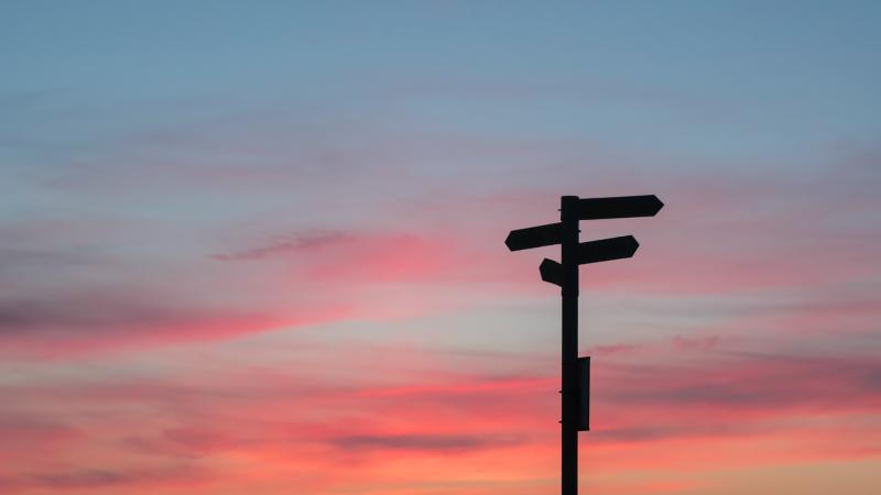 Directional signs in front of sunset sky