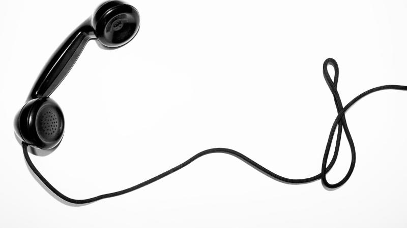 Black telephone and cord against a white background