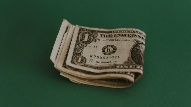 A folded stack of dollar bills on a green background